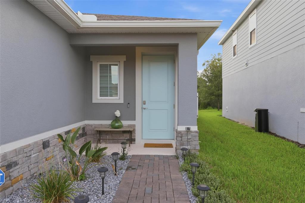 A light blue front door sits under a covered porch with stone veneer accents — 7068 LANIER FALLS ROAD, DELAND, FL