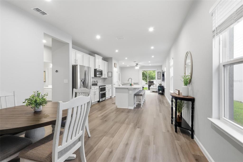 An open-concept kitchen and dining area features white cabinetry, a center island, and wood-look flooring — 7068 LANIER FALLS ROAD, DELAND, FL