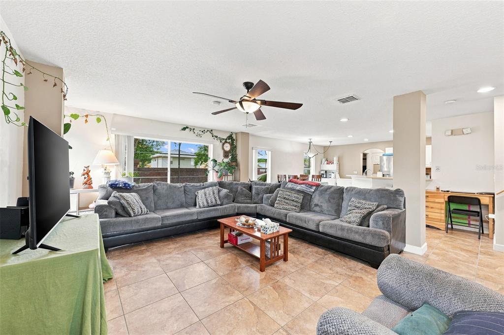 A spacious living room features a large grey sectional sofa, tile flooring, and a ceiling fan — 611 ABACO COURT, KISSIMMEE, FL