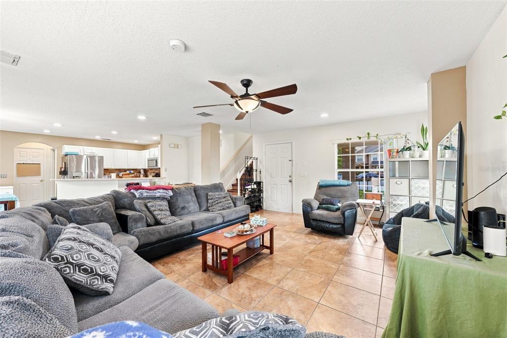 A living room with tile flooring, a grey sectional sofa, and an open kitchen — 611 ABACO COURT, KISSIMMEE, FL