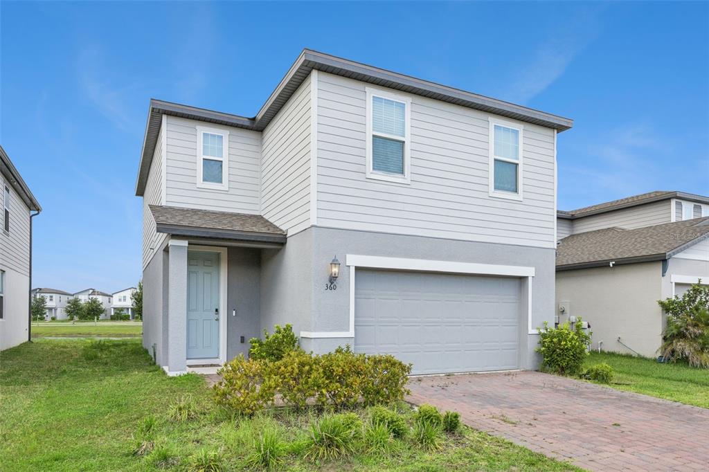 A two-story house with light gray siding, a stucco lower level, and a two-car garage — 360 WHISTLING DUCK TRAIL, ST CLOUD, FL