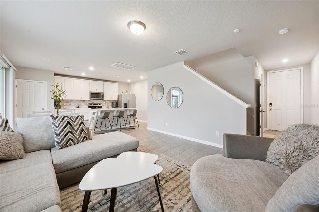 An open-concept living room and kitchen area with light gray walls and tile flooring — 360 WHISTLING DUCK TRAIL, ST CLOUD, FL