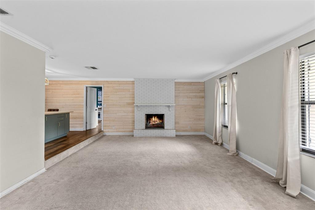 A living room features a white brick fireplace, wood-paneled walls, and carpeted flooring — 442 HOMER AVENUE, LONGWOOD, FL