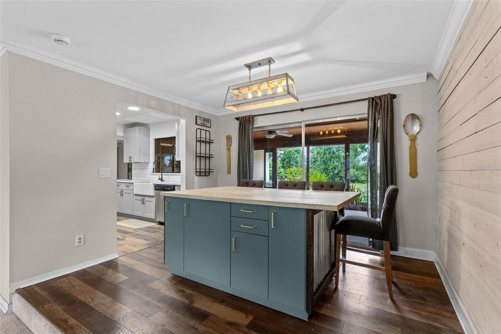 A kitchen features a blue island with a wood countertop, wood flooring, and shiplap wall — 442 HOMER AVENUE, LONGWOOD, FL