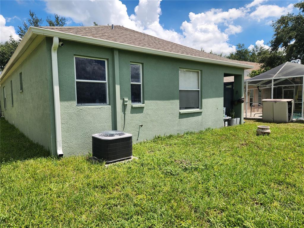 The exterior of a green stucco house features an air conditioning unit and a screened patio — 6210 KITERIDGE DRIVE, LITHIA, FL