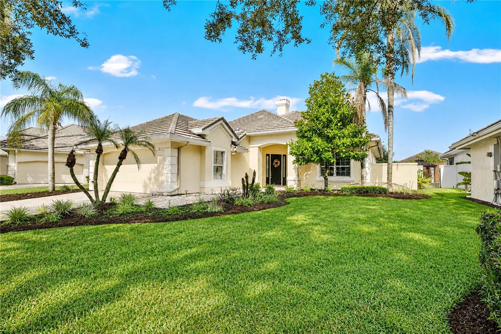 A single-story suburban house with a tan stucco exterior, tile roof, and landscaped front yard — 10842 WOODCHASE CIRCLE, ORLANDO, FL