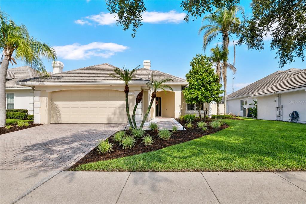A single-story house with a beige stucco exterior, a tiled roof, and a paved driveway — 10842 WOODCHASE CIRCLE, ORLANDO, FL