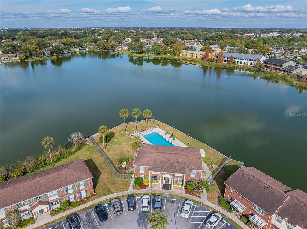 An aerial view shows a multi-story apartment building with a swimming pool beside a lake — 1920 E EDGEWOOD DRIVE UNIT L4, LAKELAND, FL
