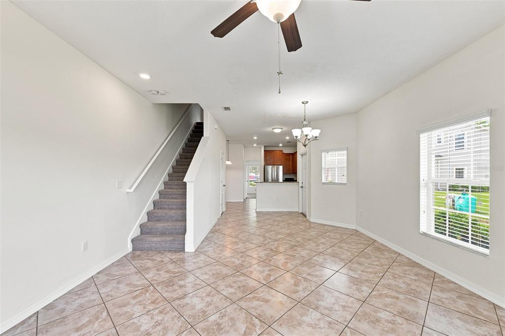 An open-concept living and dining area features tile flooring, a staircase, and a kitchen — 31141 CLARIDGE PLACE, WESLEY CHAPEL, FL