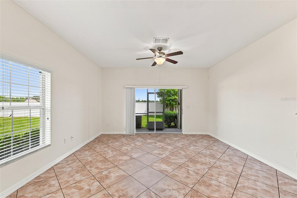 A room with beige walls, tiled floors, a ceiling fan, and sliding glass patio doors — 31141 CLARIDGE PLACE, WESLEY CHAPEL, FL