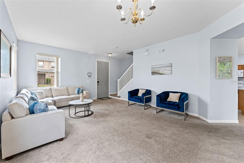 A living room features a beige sectional sofa, two blue velvet chairs, and a chandelier — 213 WILLOW VIEW DRIVE, DAVENPORT, FL