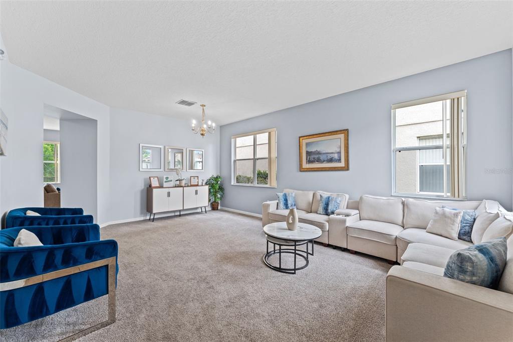 A living room features a large sectional sofa, blue velvet chairs, and a marble coffee table — 213 WILLOW VIEW DRIVE, DAVENPORT, FL