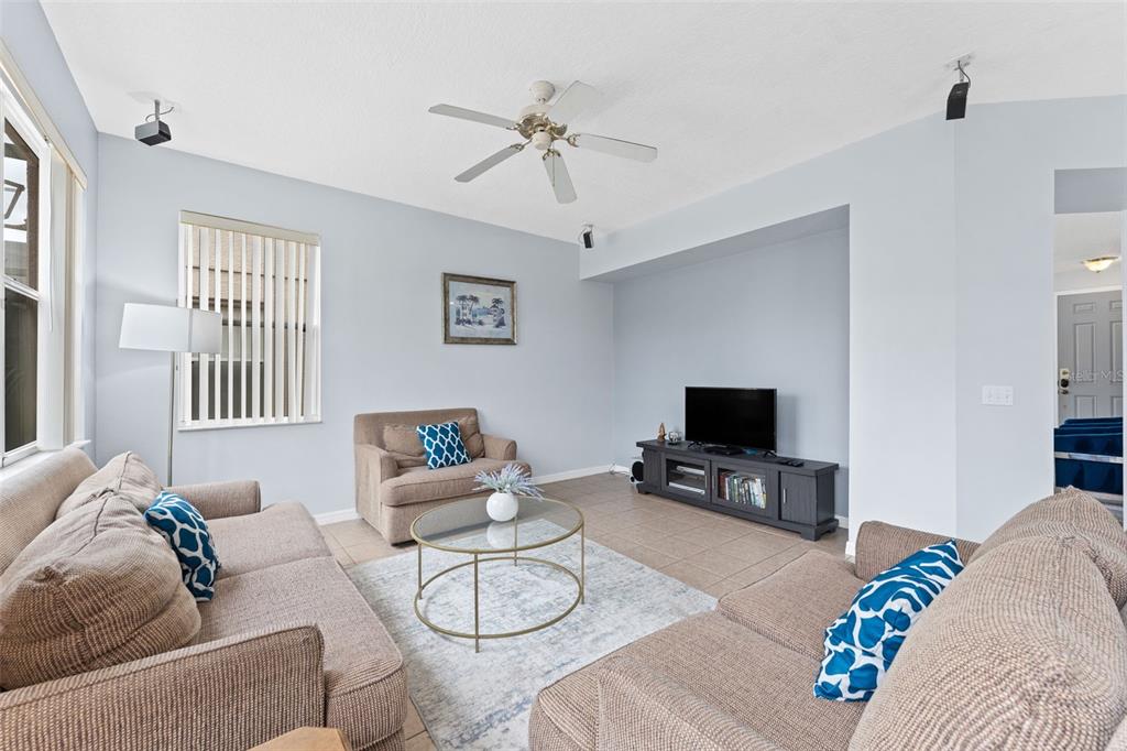 A living room features light blue walls, beige furniture, a glass coffee table, and tile flooring — 213 WILLOW VIEW DRIVE, DAVENPORT, FL