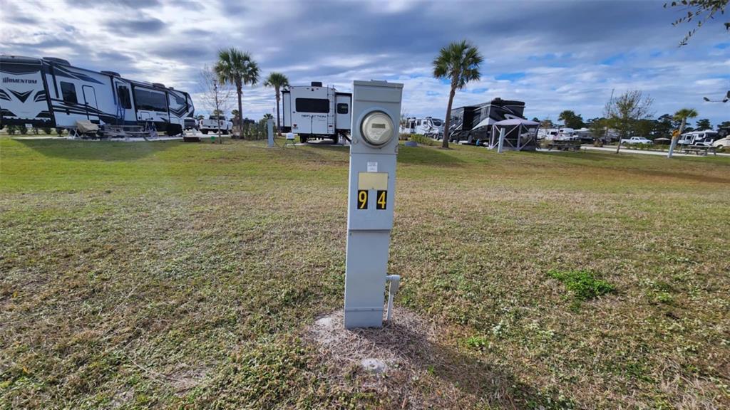 A utility pedestal labeled 94 stands in a grassy RV park with several parked trailers — 94 CEDAR CIRCLE E, LAKE WALES, FL