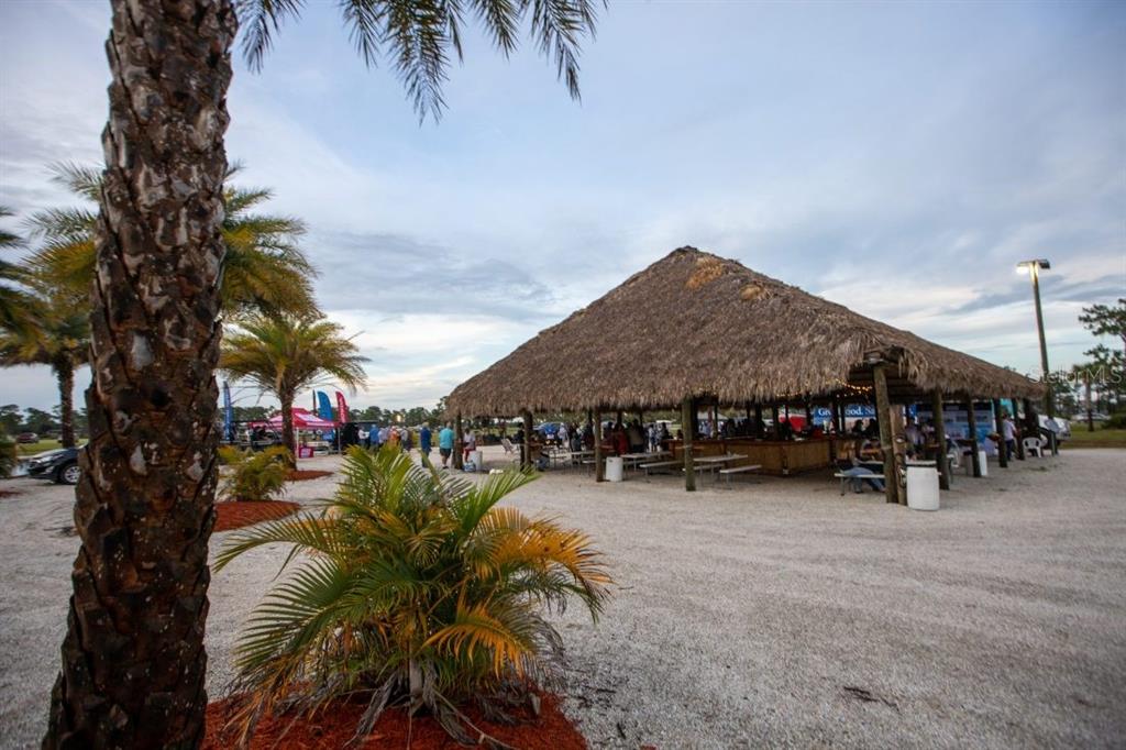 A large, open-air tiki hut with a thatched roof sits on a gravel lot — 94 CEDAR CIRCLE E, LAKE WALES, FL