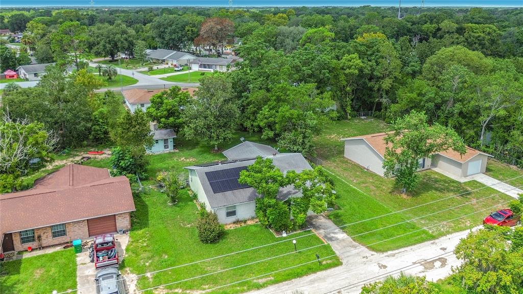 An aerial view shows three suburban houses surrounded by lush green trees and grassy lawns — 9320 SE MARICAMP ROAD, OCALA, FL