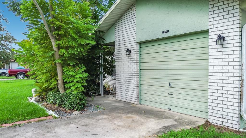 A light green garage door is set into a white brick exterior wall of a house — 9320 SE MARICAMP ROAD, OCALA, FL
