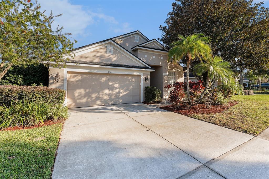 A single-story house with a beige stucco exterior, a two-car garage, and a concrete driveway — 3316 STONEBRIDGE TRAIL, VALRICO, FL