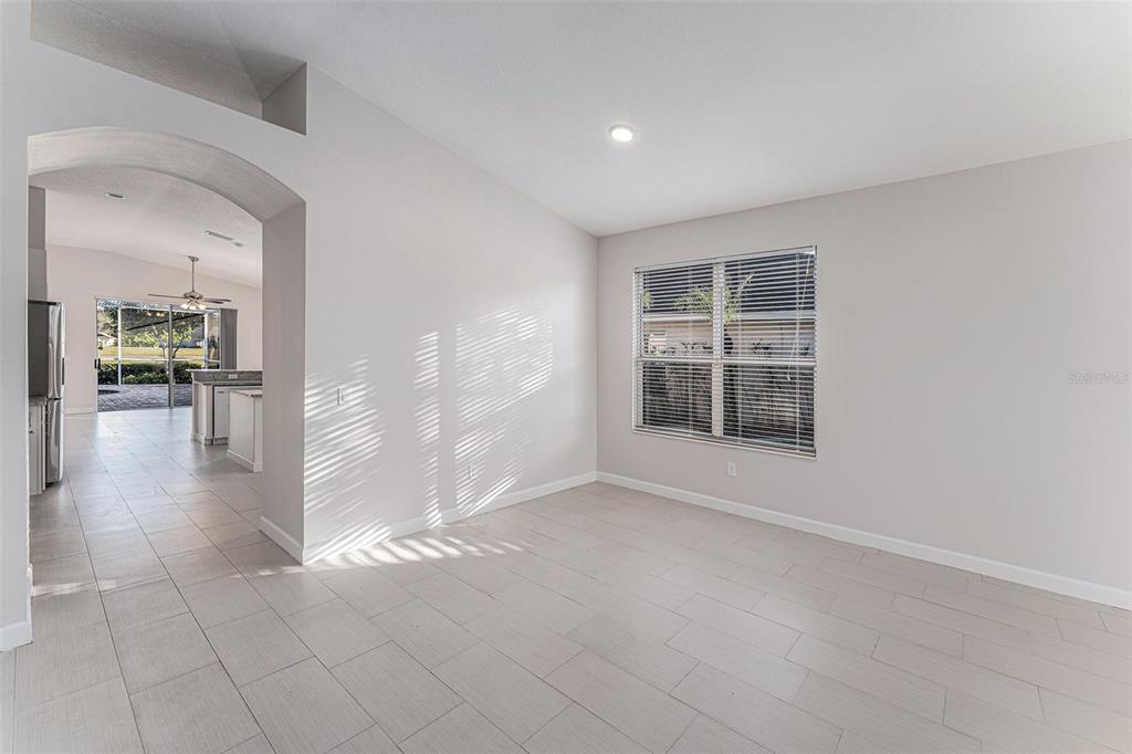 A bright room with light-colored tile flooring, an arched entryway, and a window with blinds — 3316 STONEBRIDGE TRAIL, VALRICO, FL