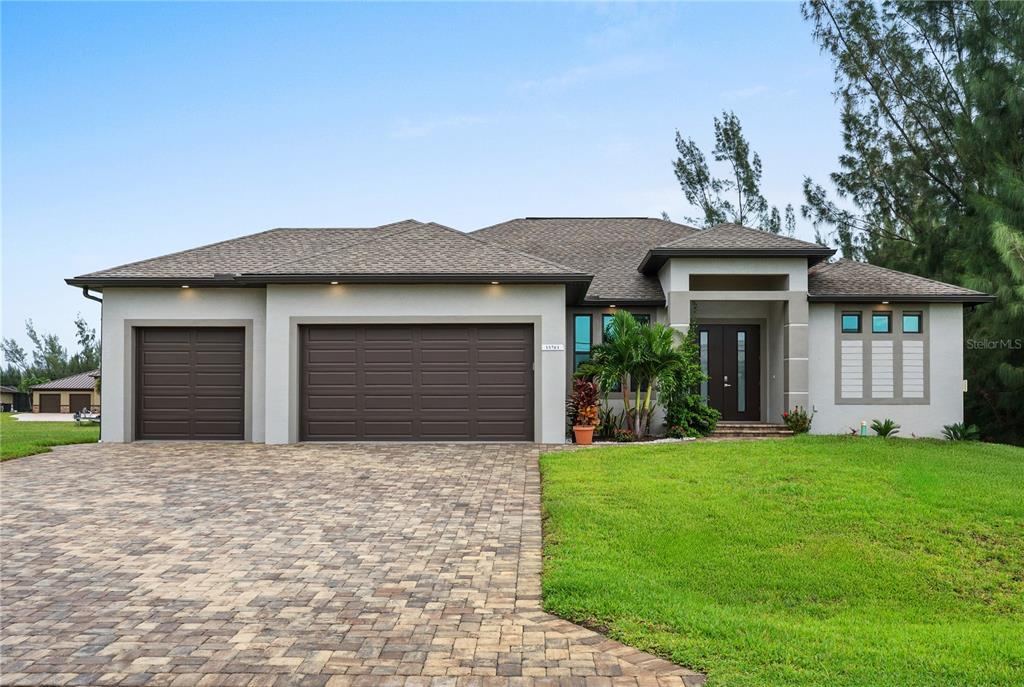 A single-story house with a three-car garage, paver driveway, and a front entryway — 15761 AQUA CIRCLE, PORT CHARLOTTE, FL