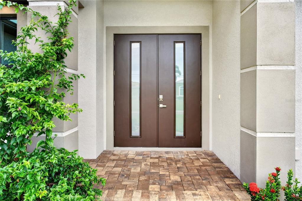 A brown double front door with vertical glass panels sits on a paved entryway — 15761 AQUA CIRCLE, PORT CHARLOTTE, FL