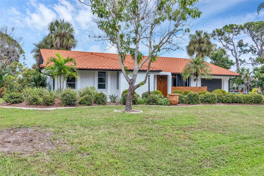 A single-story house with a red tile roof, white exterior, and lush landscaping — 4696 POMPANO STREET, PLACIDA, FL