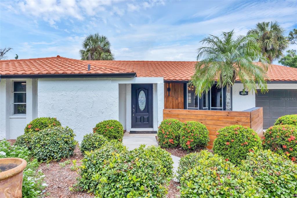 A white house with a terracotta tile roof, a dark front door, and manicured landscaping — 4696 POMPANO STREET, PLACIDA, FL