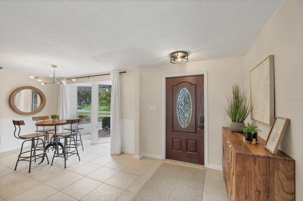 An entryway and dining area featuring tile floors, a wooden front door, and a bistro table — 4696 POMPANO STREET, PLACIDA, FL