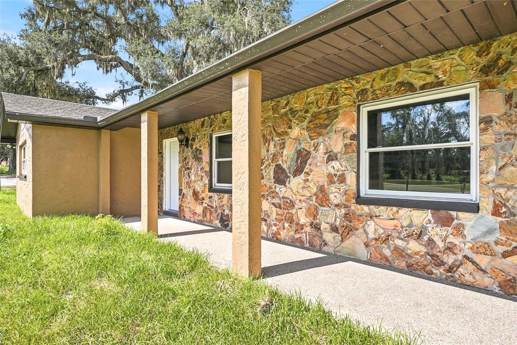 A stone-faced house exterior features a covered concrete porch with tan support columns — 37670 FARR ROAD, DADE CITY, FL