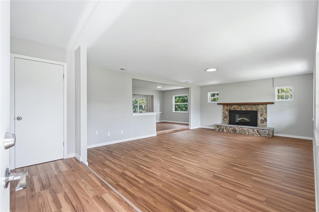 A living room features light gray walls, wood-look flooring, and a stone fireplace — 37670 FARR ROAD, DADE CITY, FL