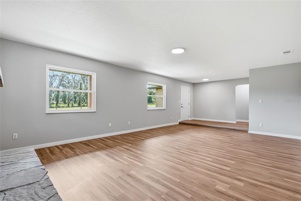 A spacious living room features light gray walls, wood-look flooring, and a stone fireplace hearth — 37670 FARR ROAD, DADE CITY, FL