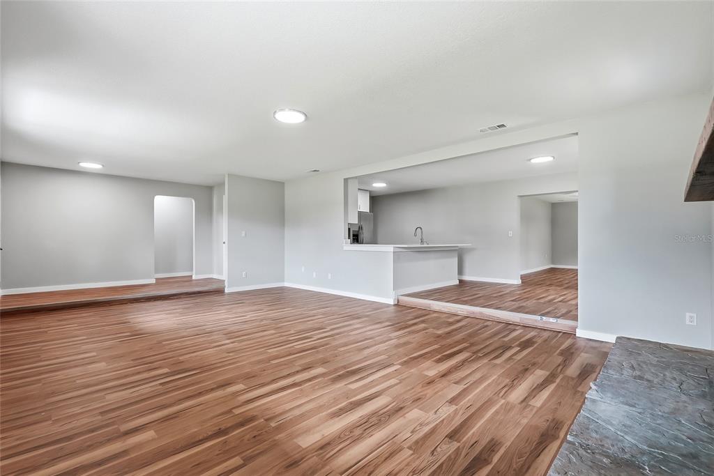 A spacious living area with wood-look flooring, recessed lighting, and a pass-through kitchen counter — 37670 FARR ROAD, DADE CITY, FL