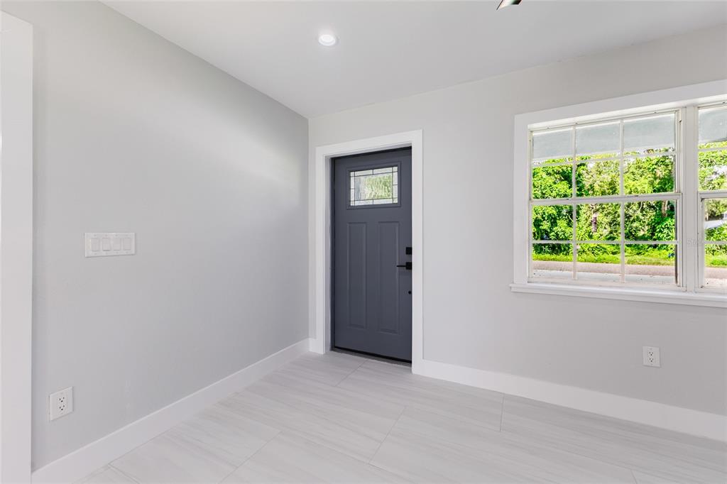 A room with light gray walls, white trim, light wood-look flooring, and a dark gray door — 639 HAND AVENUE, SARASOTA, FL