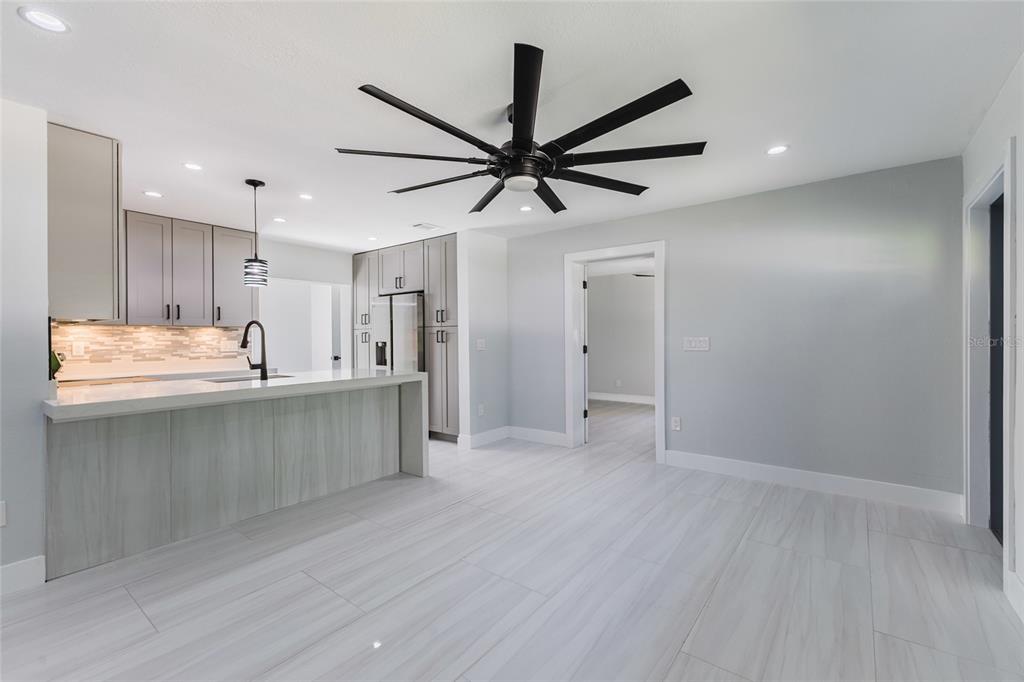 A modern kitchen features gray cabinetry, a white waterfall island, and a large ceiling fan — 639 HAND AVENUE, SARASOTA, FL