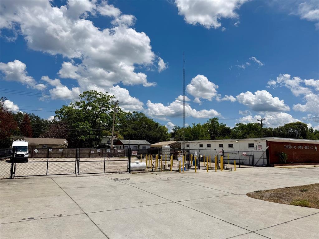 A paved outdoor lot features yellow bollards, a white van, and a wooden fence — 414 W 9TH STREET, SANFORD, FL