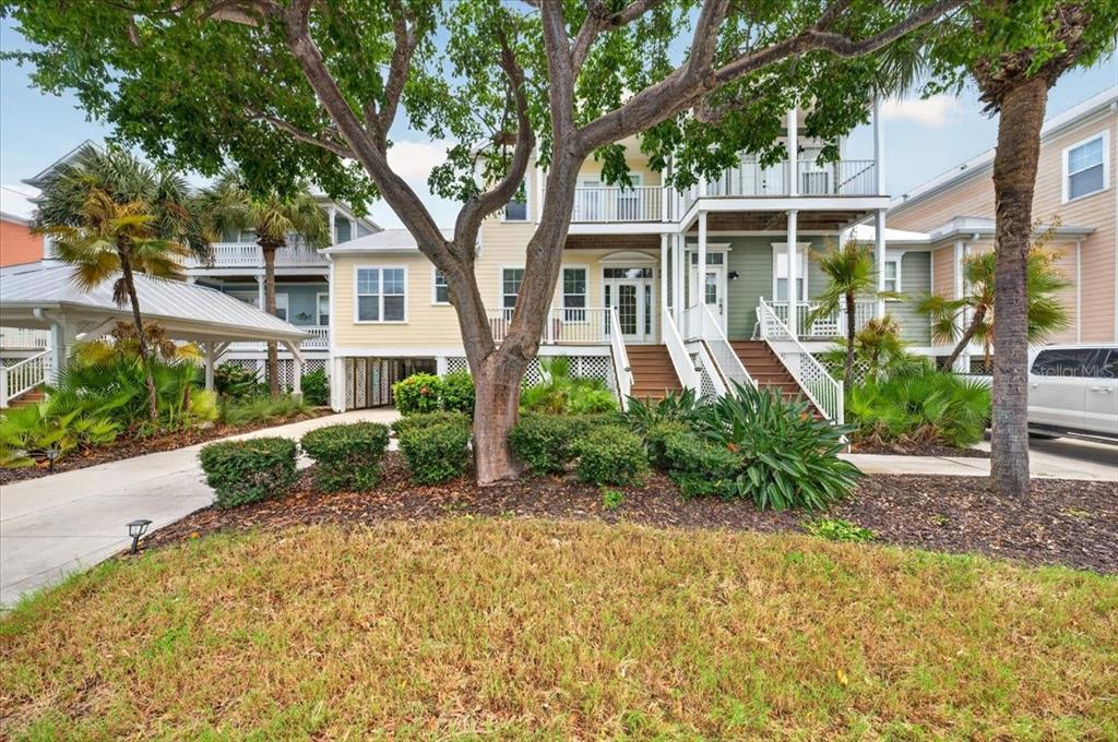 A multi-story house with a yellow and green exterior, elevated porches, and a large tree — 11764 ANGLERS CLUB DRIVE UNIT 111, PLACIDA, FL