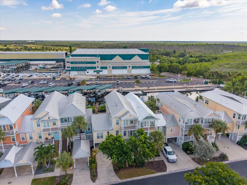An aerial view shows a row of coastal houses near a marina and large warehouse — 11764 ANGLERS CLUB DRIVE UNIT 111, PLACIDA, FL