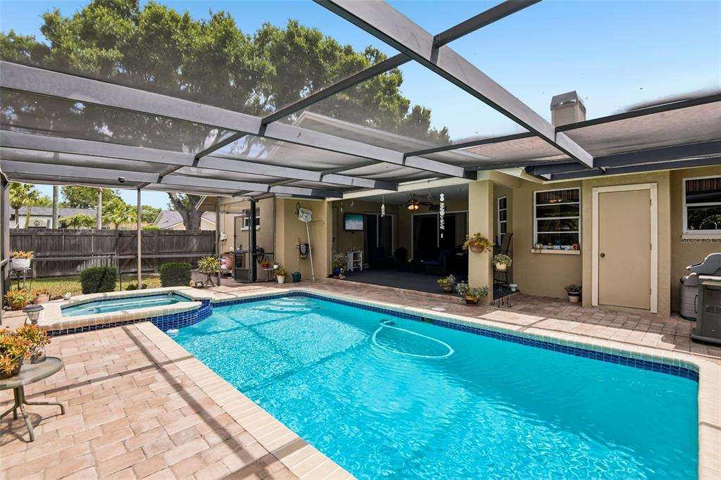 A screened-in patio features a swimming pool, a raised spa, and a covered seating area — 12596 93RD WAY, LARGO, FL