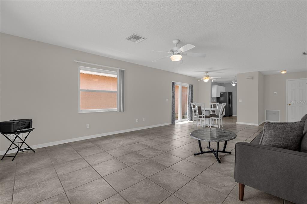 A living room with gray tile flooring, a ceiling fan, and an adjacent dining area — 805 SAN CARLOS COURT, LADY LAKE, FL
