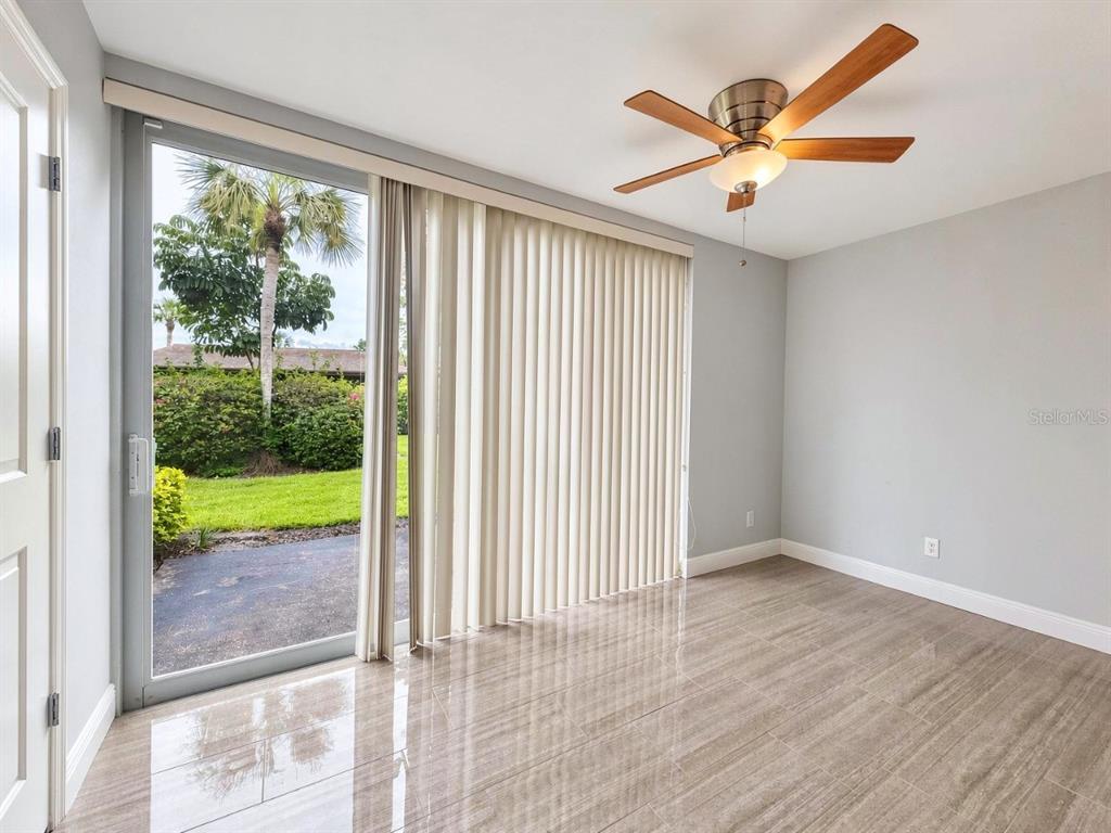 A room with light gray walls, tile flooring, a ceiling fan, and sliding glass doors — 681 PALM VIEW DRIVE UNIT C1, NAPLES, FL