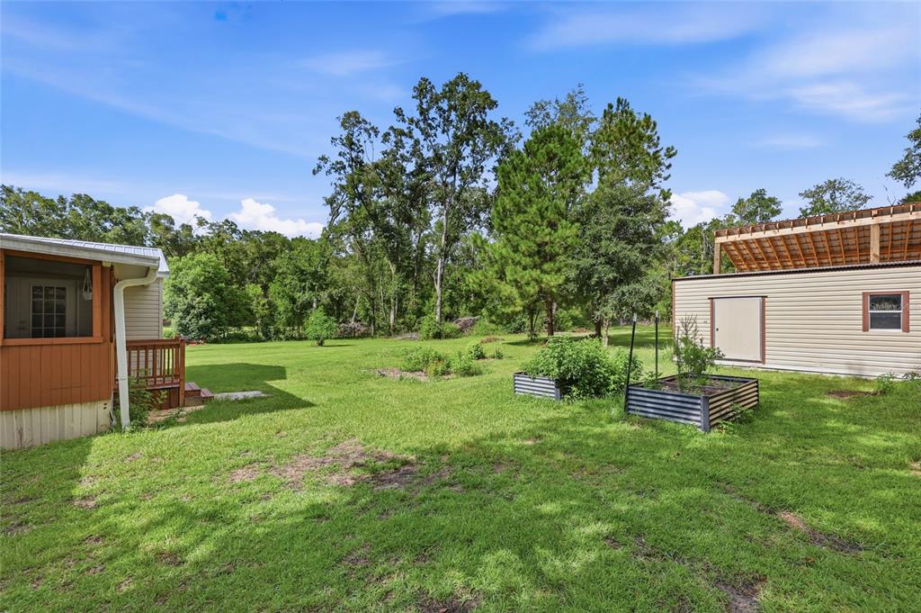 A spacious living area with light blue walls, gray tile flooring, and a vaulted ceiling — 9528 NW 235TH TERRACE, ALACHUA, FL