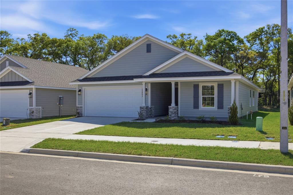 A single-story house with light blue siding, a two-car garage, and a covered front porch — 2618 SW 250TH TERRACE, NEWBERRY, FL