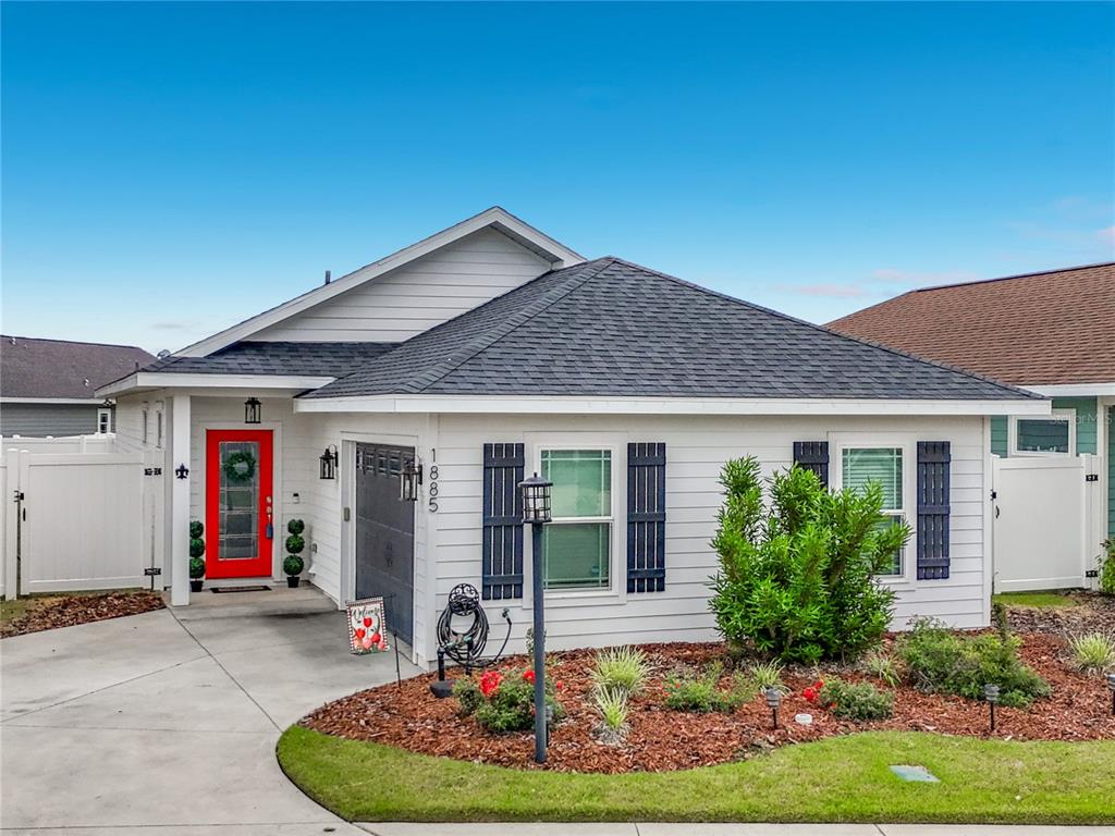 A white single-story house features a red front door, dark shutters, and a landscaped yard — 1885 SW 245TH TERRACE, NEWBERRY, FL