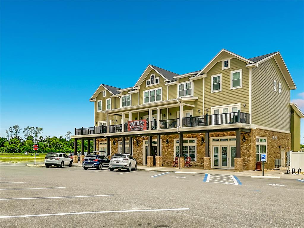 A three-story building with green siding and a stone facade features a second-story balcony — 1885 SW 245TH TERRACE, NEWBERRY, FL