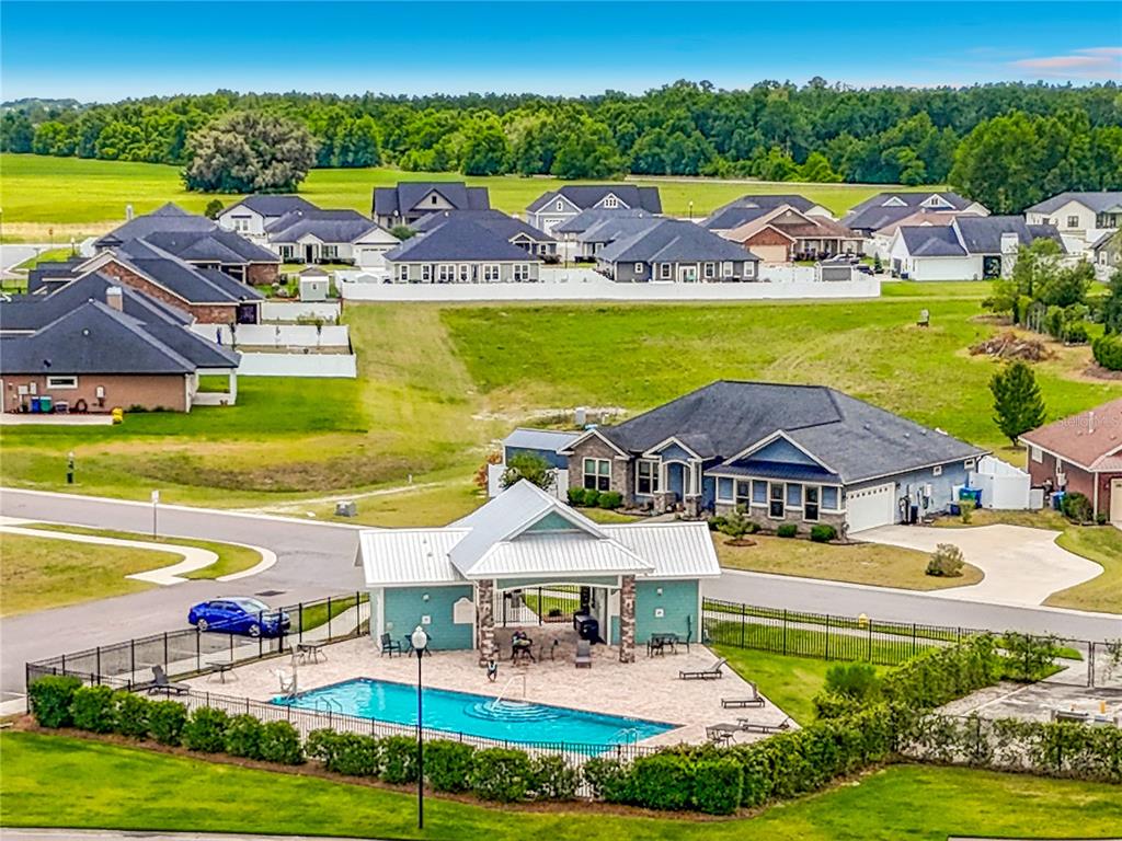An aerial view shows a community swimming pool and pavilion surrounded by suburban houses — 1885 SW 245TH TERRACE, NEWBERRY, FL