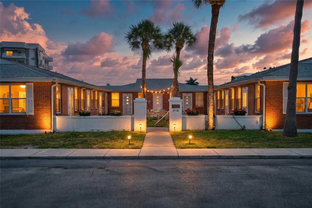 A U-shaped brick apartment complex with a central courtyard, palm trees, and exterior lighting — 908 VILLAS DRIVE UNIT 23, VENICE, FL
