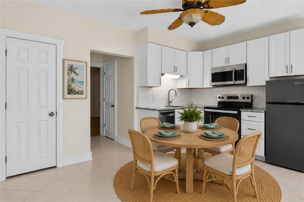 A kitchen features white cabinets, stainless steel appliances, and a round wooden dining table — 908 VILLAS DRIVE UNIT 23, VENICE, FL
