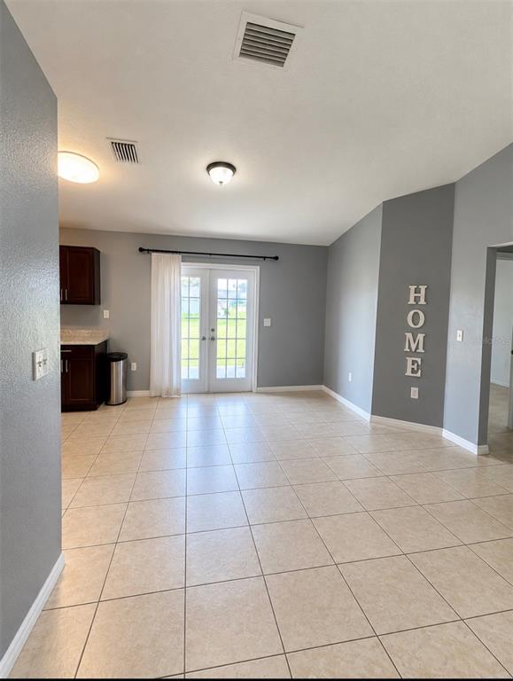 A room with tiled floors, gray walls, and French doors leading to a backyard patio — 61 WALNUT DRIVE, OCALA, FL
