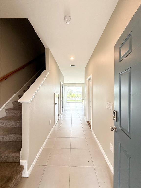 An entryway with tiled flooring leads to a staircase and a view of the outdoors — 2309 ALEE LANE, WESLEY CHAPEL, FL