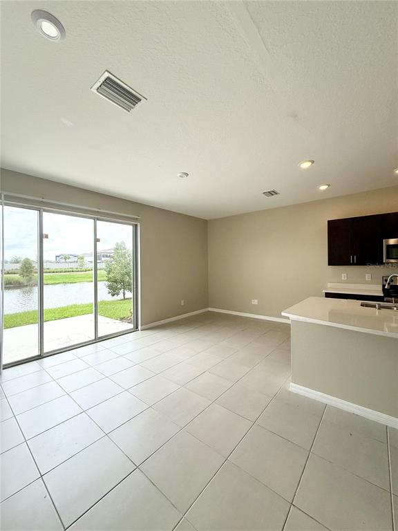 A kitchen and living area with tile floors, recessed lighting, and sliding glass doors to a lake — 2309 ALEE LANE, WESLEY CHAPEL, FL